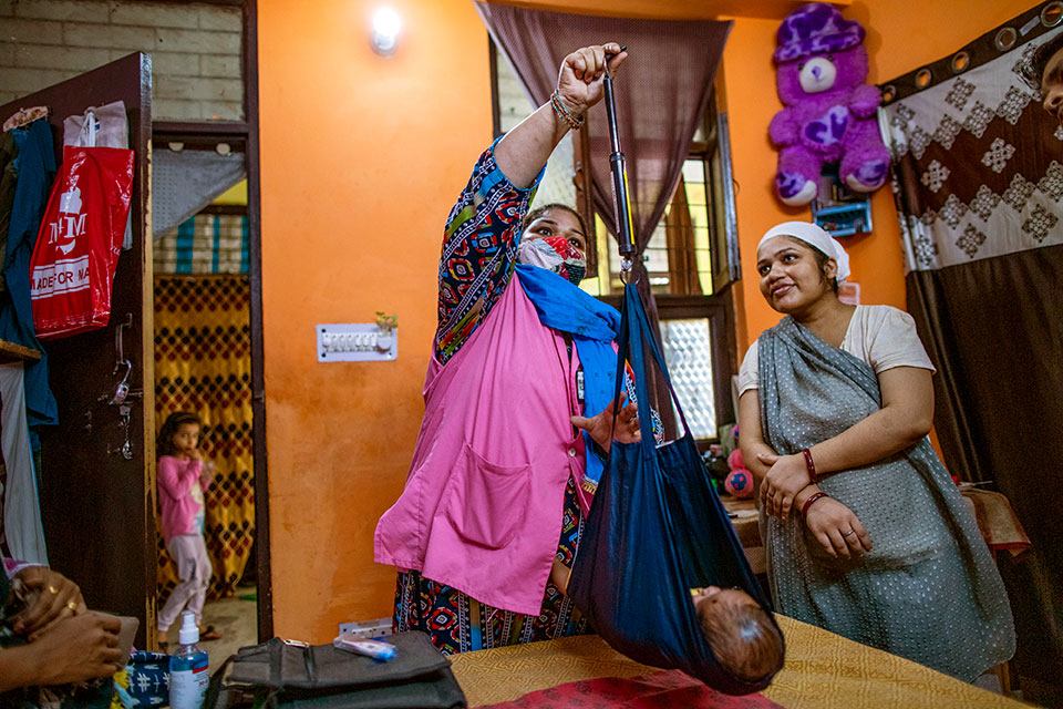 Salma Lari, an accredited social health worker with ASHA and a member of Mahila Panchayat (women’s local council) weighs a 27-day-old baby as part of her home visits providing pre- and post-natal health check-ups in the Batla House area of New Delhi. Photo: UN Women/ Prashanth Vishwanathan