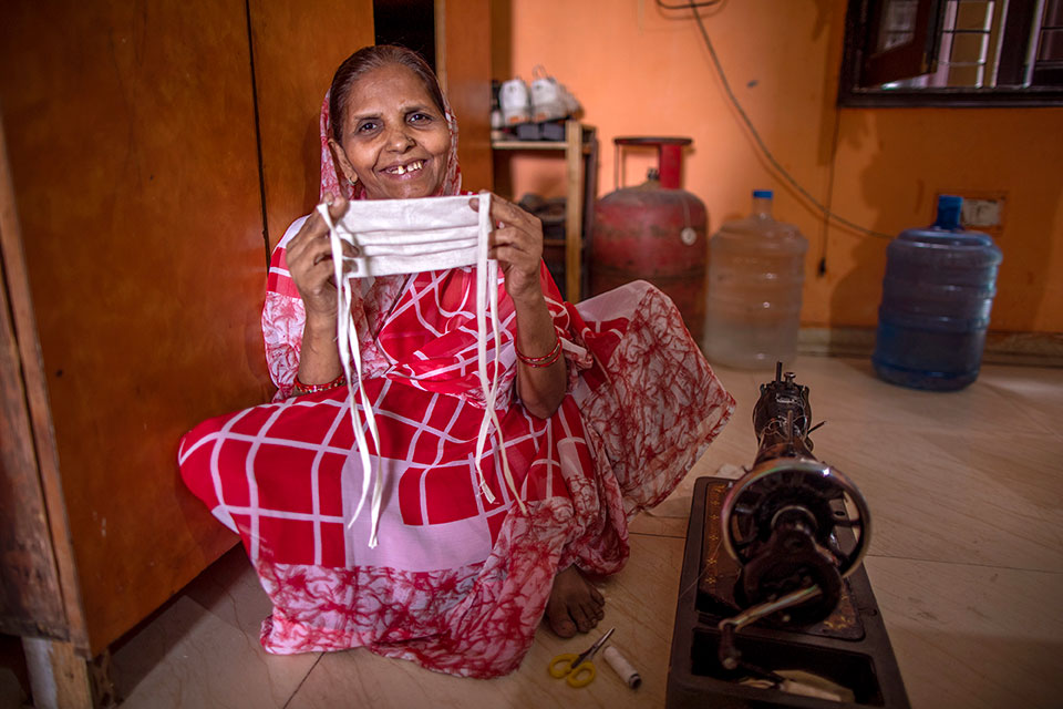Laxmi Devi, 55, shows a mask she has made. She is using the sewing machine that she bought with a loan received through SEWA to make and sell masks in New Ashok Nagar neighbourhood of New Delhi. Her mindset about women and work has changed. When she was younger, women didn’t work, but she says now are different. “Girls should go out and work now. Boys and girls are equal,” she says. Photo: UN Women/ Prashanth VIshwanathan
