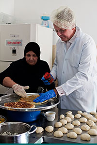 UN Women Deputy Executive Director John Hendra participates in a demonstration of the Women-Run School Canteen Project at the Anata Sabaya Centre.Photo: UN Women/Loulou d'Aki