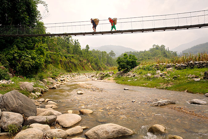 Chandra Kala Thapa and Bir Bahadur Thapa carry newly-harvested vegetables to sell in a nearby village. Photo: UN Women/Narendra Shrestha