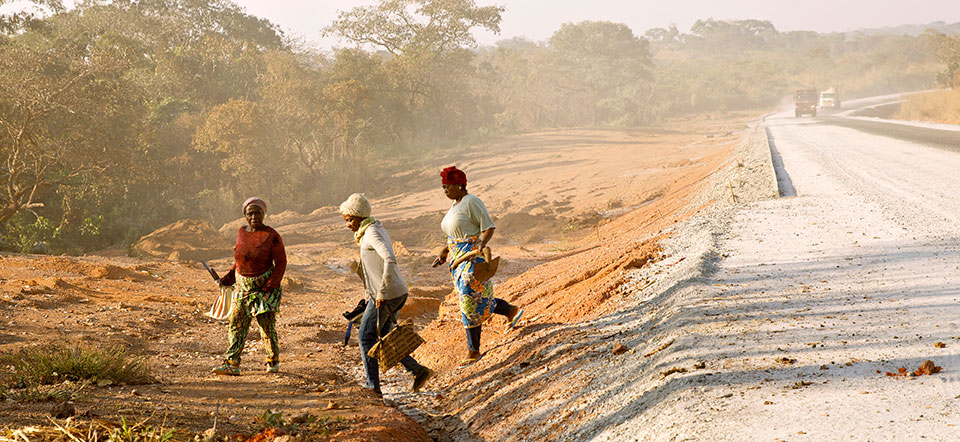 Members of SOCCOMAD arrive to work on a collective plot of land near a newly-completed section of road. Photo: UN Women/Ryan Brown