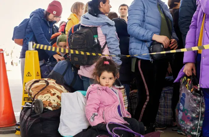 A young girl looks sits with luggage alongside a crowd of refugees at the Mayaki-Udobnoe Border crossing in southeastern Moldova. 