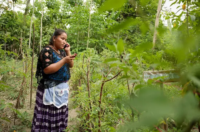 Elena Sam Pec, pictured as she takes a phone call on one phone while checking a text message on another, lives in Puente Viejo, Guatemala, a mostly agrarian indigenous community that relies on wooden canoes to transport their products or to access services. Digital technology can help better connect rural women like Elena with services and resources, but a lack of inclusive design means marginalized groups often stand to benefit least from new innovations. Photo: UN Women/Ryan Brown 
