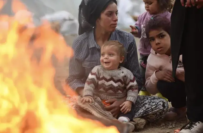 Survivors of the 7.7 magnitude earthquake keep warm by a fire in a temporary shelter in Kahramanmaraş, Turkey. The affected region of south-east Turkey and Syria was already severely disrupted by the nearly 12-year conflict in Syria, and ethnic tensions in Turkey. Photo: UNICEF/Ölçer