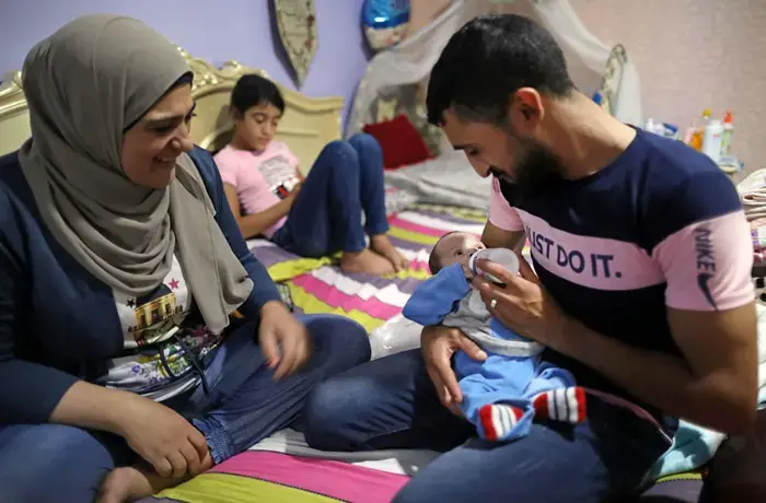 A man is seeing feeding a baby in Tyre, Lebanon, in 2020. 