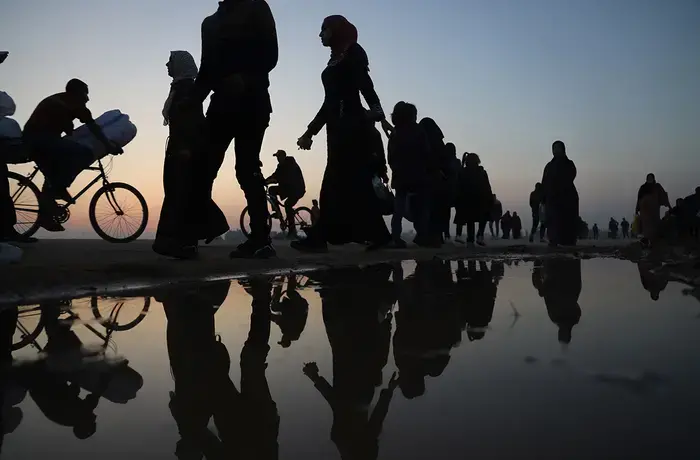 During the sunset, Palestinians walk next to the sea in the city of Rafah, in the southern Gaza Strip, on 8 January 2024.