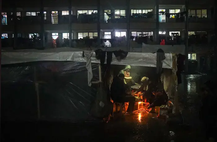 A Palestinian family is seen at a shelter during a rainy night in the city of Rafah, Gaza.