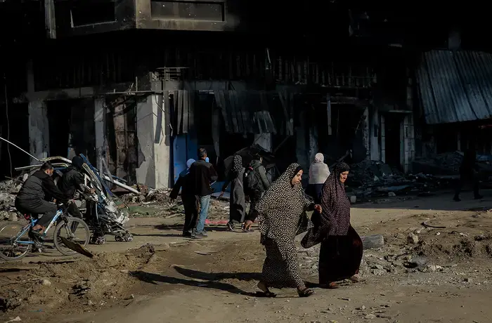 Two women cross the road and are surrounded by destroyed buildings at al-Jalaa Street in the center of Gaza City on 11 January 2024.