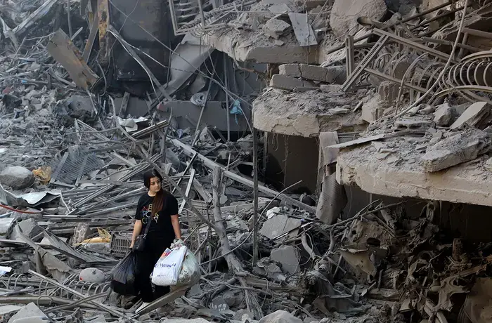 On 29 September 2024 a woman in Beirut, Lebanon walks among the debris of buildings destroyed by airstrikes.