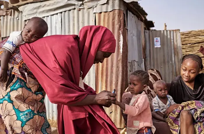 A woman delivers a vaccine to a small child
