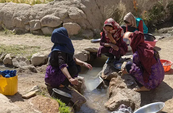 Afghan women gathered together and washing cookware