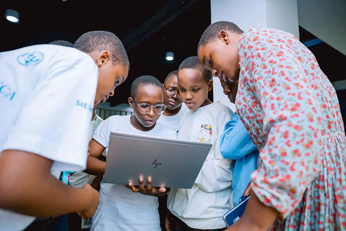 Des jeunes femmes travaillent ensemble sur un ordinateur portable lors d'un atelier d'entraînement au codage de l'initiative « African Girls Can Code » qui s'est tenu au Centre de transformation numérique de GIZ à Kigali, au Rwanda, en avril 2024. Photo : ONU Femmes