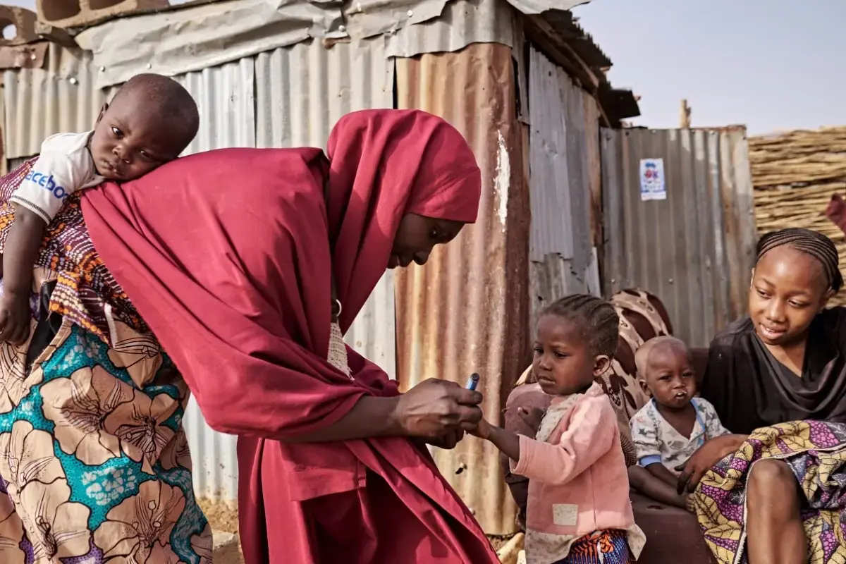 A woman delivers a vaccine to a small child