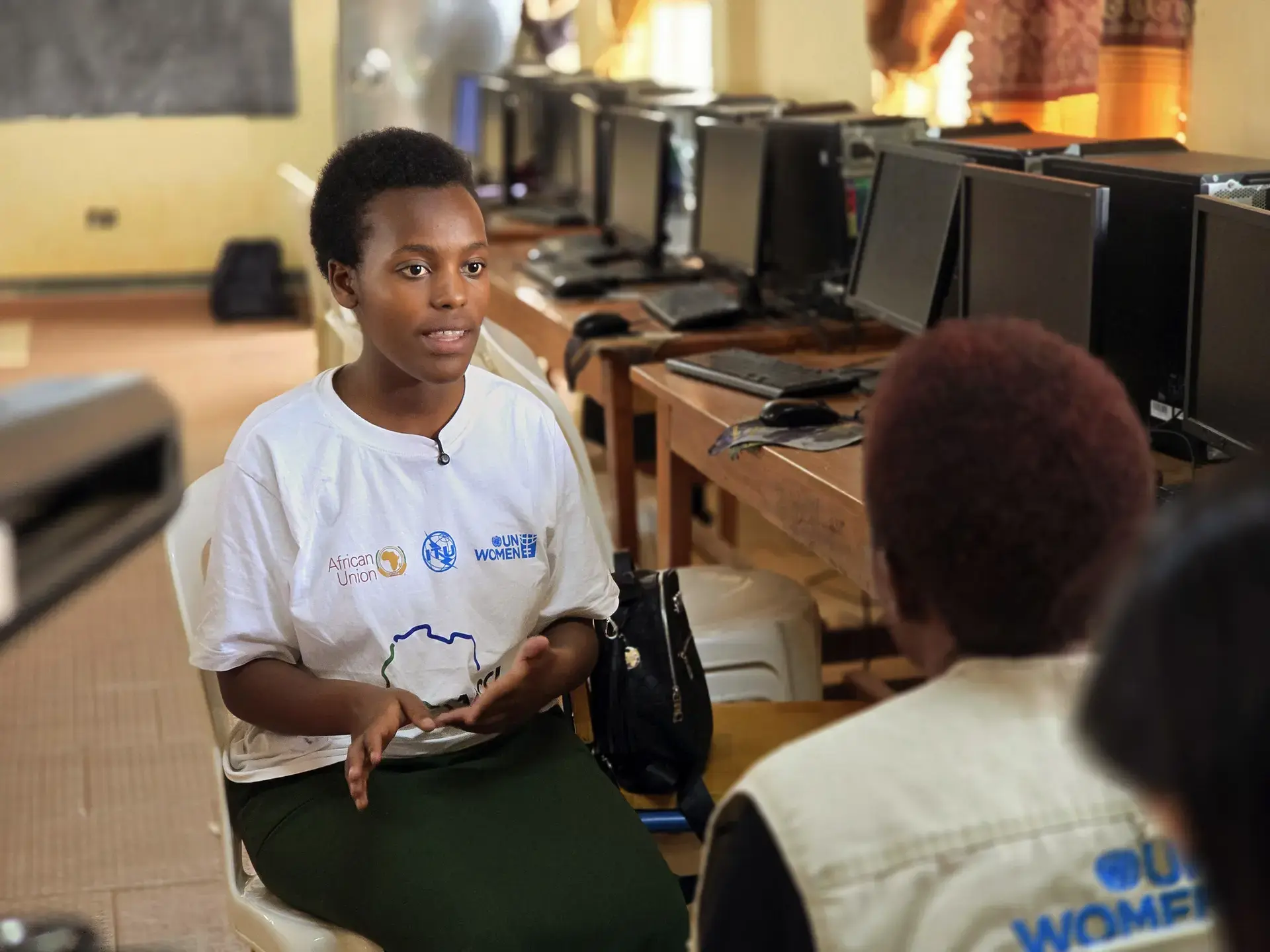 Victoria Komekyeya sits in a computer lab and speaks with UN Women staff