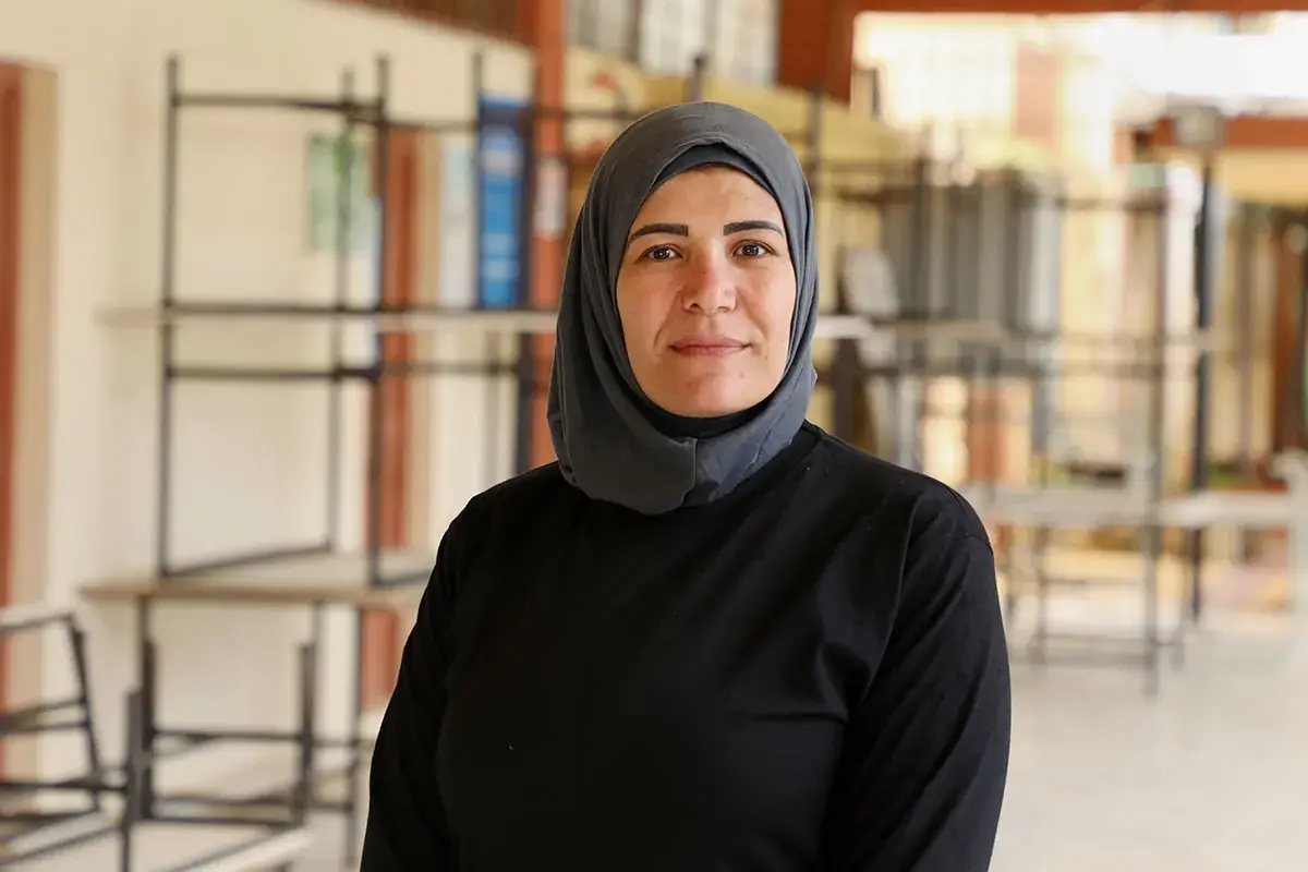 A woman poses for a portrait wearing a black dress and gray headscarf