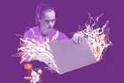 Collage with photo and illustration. A young woman with a serious expression opens a laptop. From inside it, aggressive, broken lines come off the device. By her side, there's a smartphone with the same white and orange lines on its screen. Pop-ups of messages suggest she's receiving violent texts.