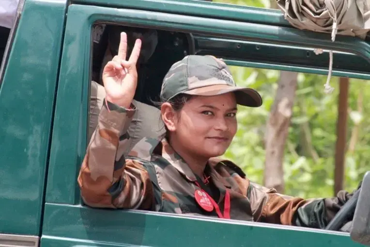 A woman driving a Jeep waves hello to the camera