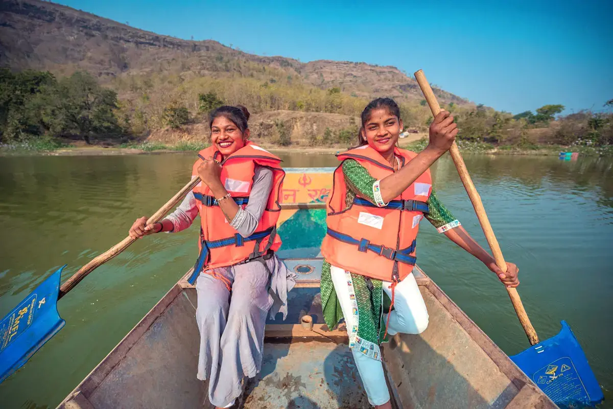 Two young women tour guides steer a boat and smile at the camera
