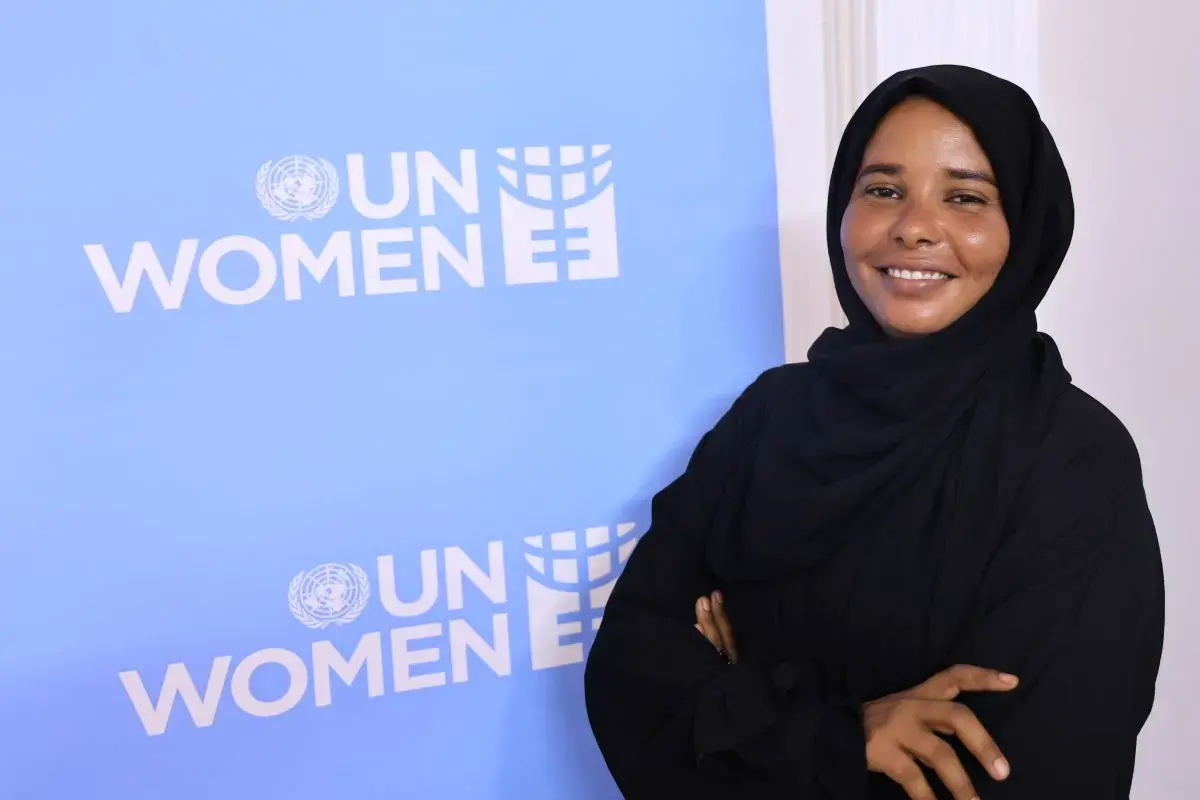 Areej Hussein, a young Sudanese woman, poses in front of a UN Women banner