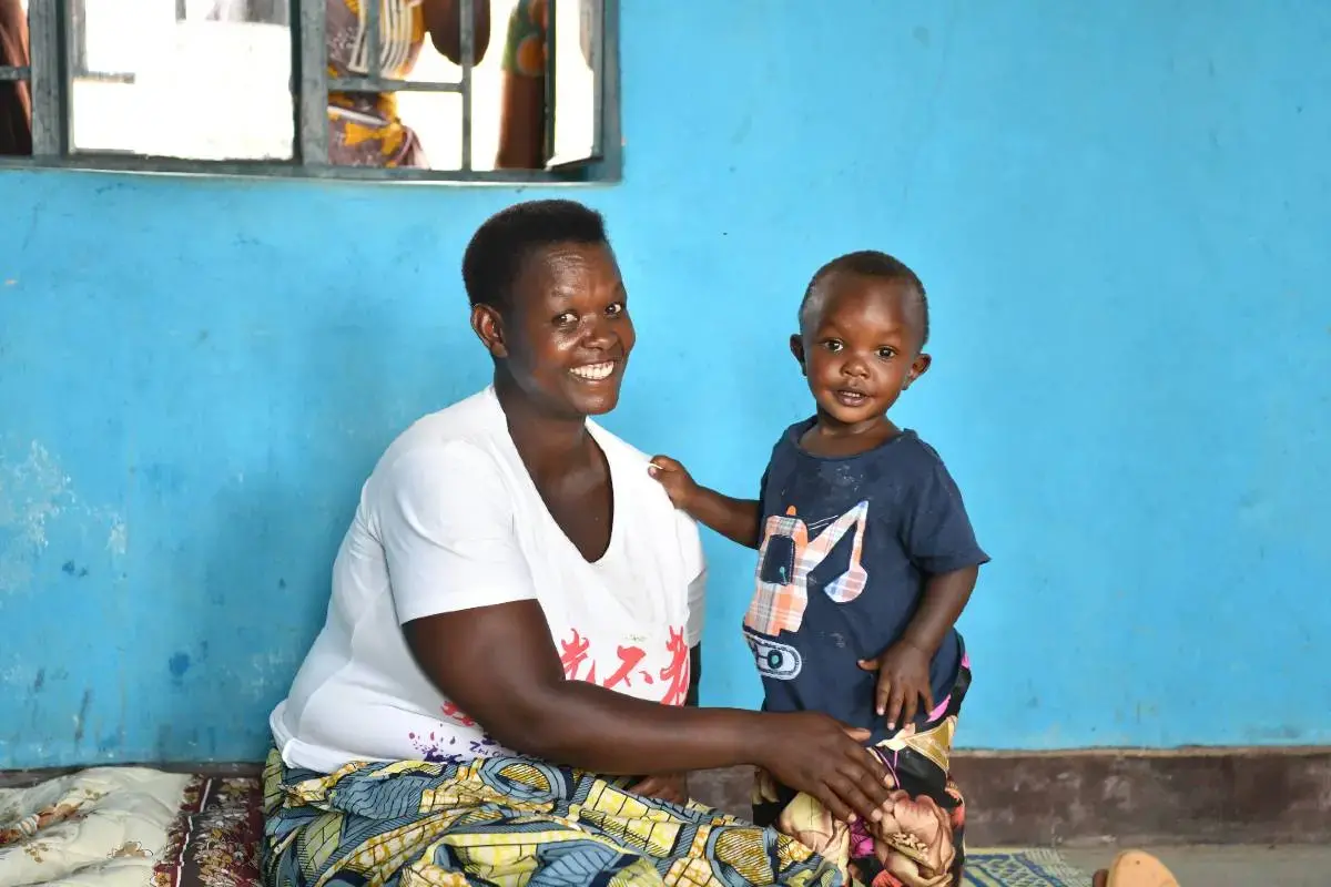 Christine Mukamana con su hijo menor en el centro de desarrollo en la primera infancia del sector Munini, distrito de Nyaruguru. Foto: ONU Mujeres Rwanda.